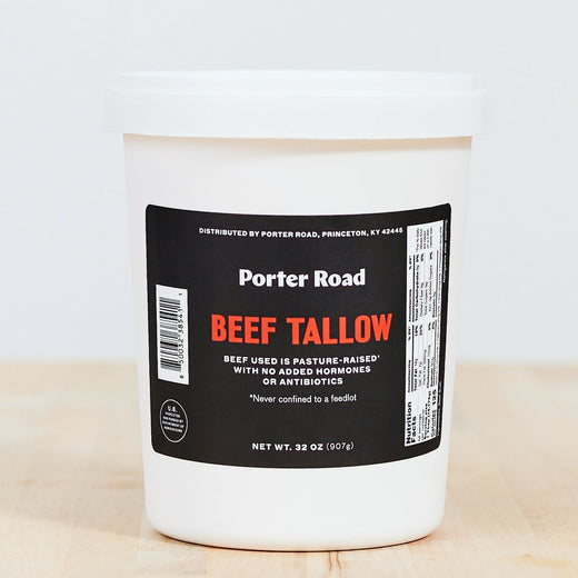 Pasture-raised beef tallow in a 32 oz container on a butcher block