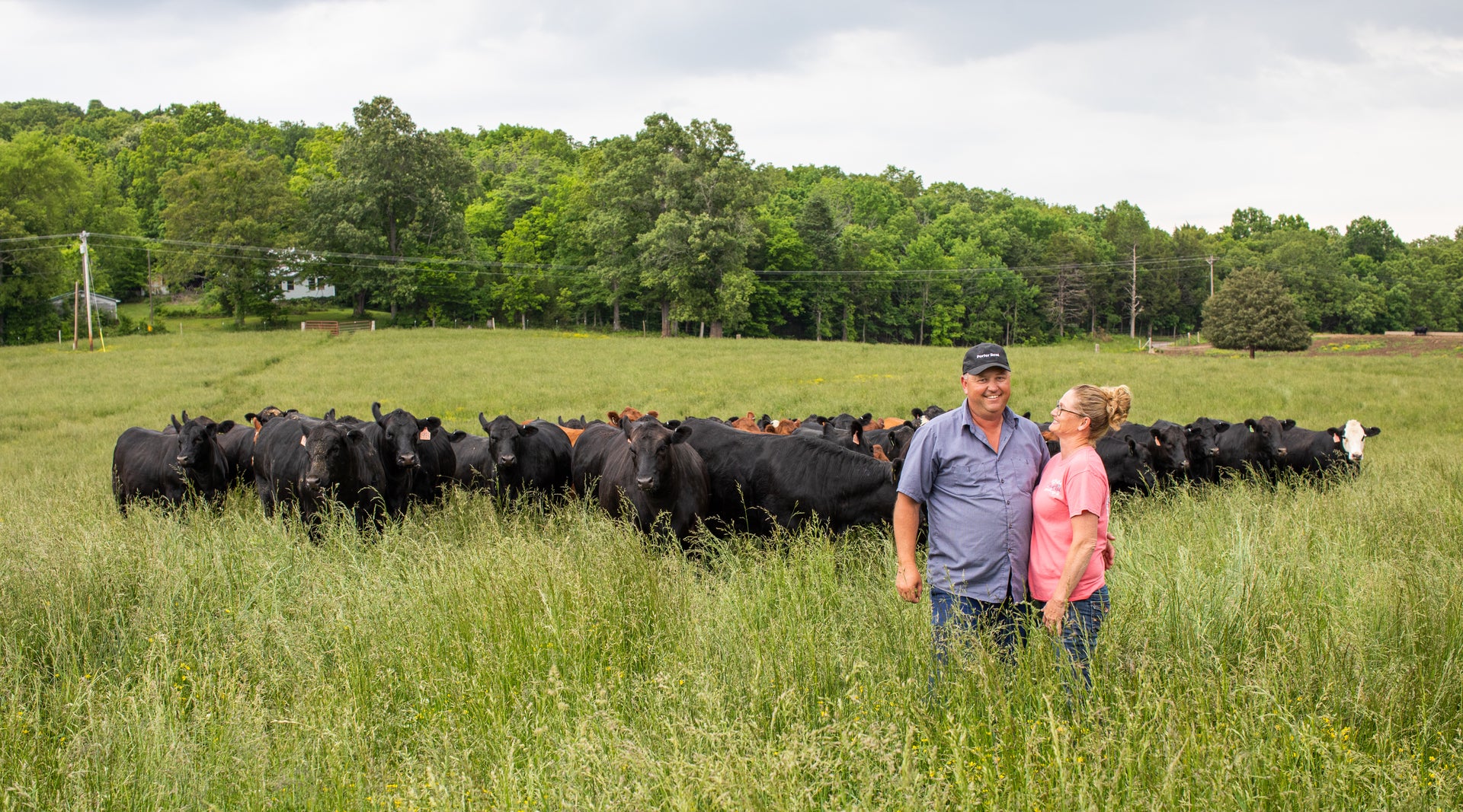 Farmer couple in pasture with cattle wearing Porter Road cap